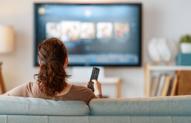 Donna che ha un telecomando in mano e guarda la tv