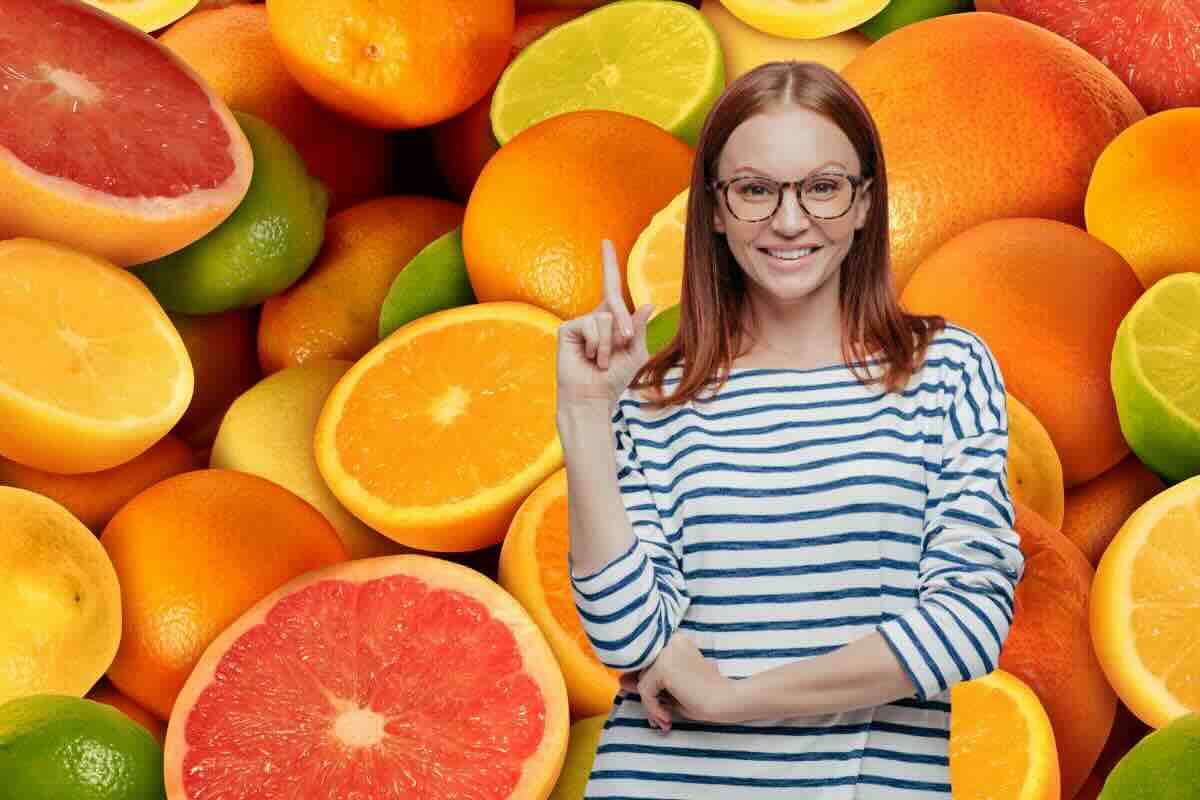 Agrumi sullo sfondo e in primo piano donna con dito rivolto verso l'alto, sorridente