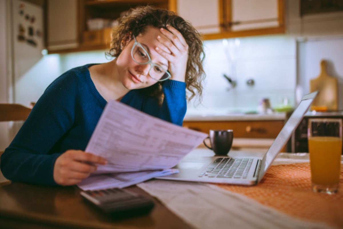 donna preoccupata mentre legge una bolletta
