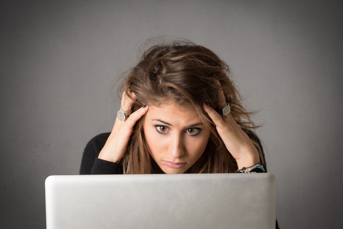 donna con le mani tra i capelli di fronte a pc