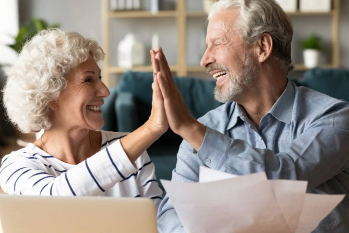 uomo e donna anziani che sorridono e battono il 5 con la mano